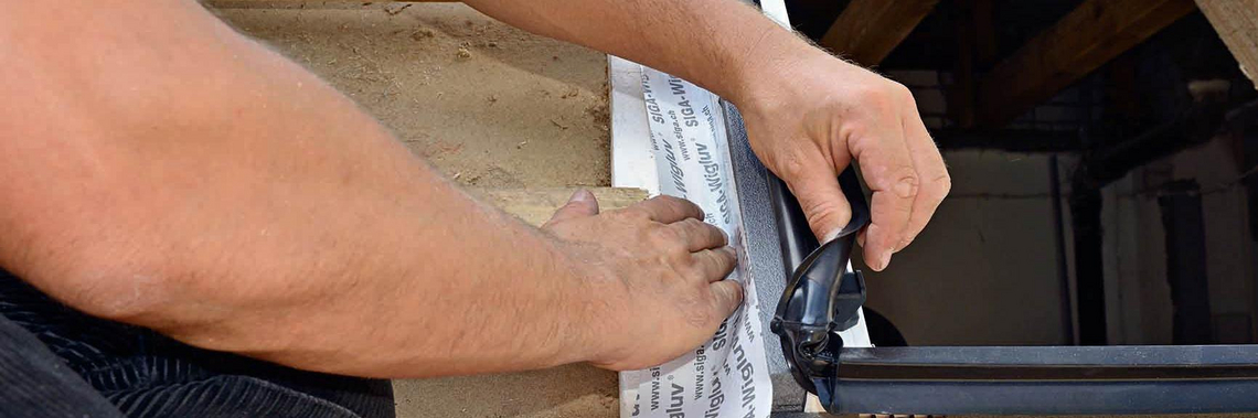 Ein Handwerker stellt eine luftdichte Ebene beim Fenstereinbau her