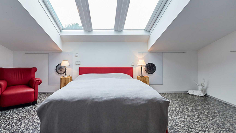 Blick in ein modern eingerichtetes Schlafzimmer mit eingebauten Dachfenstern